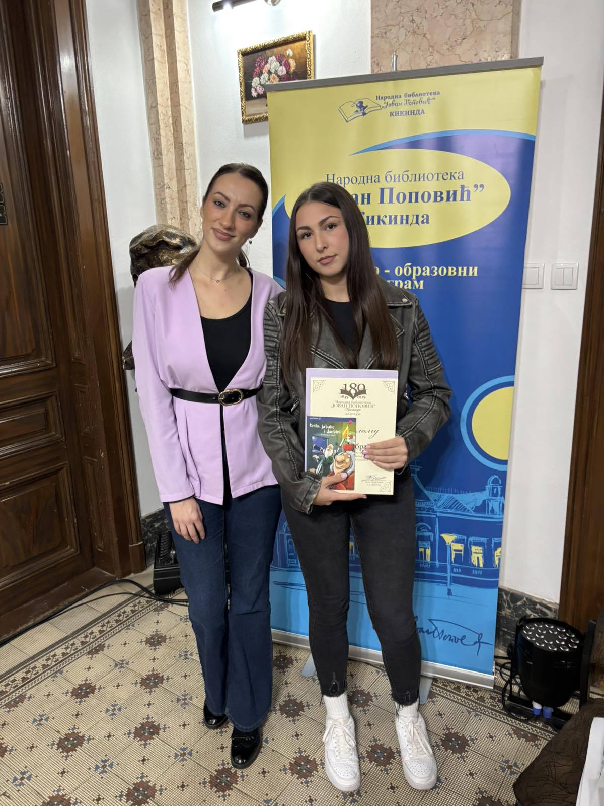 Two women standing in front of a banner
AI-generated content may be incorrect.